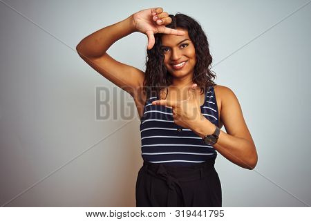 Transsexual transgender woman wearing striped t-shirt over isolated white background smiling making frame with hands and fingers with happy face. Creativity and photography concept.