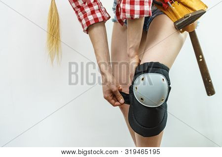 Unrecognizable Woman Wearing And Adjusting Her Safety Knee Protectors Pads. Safe Workwear During Con