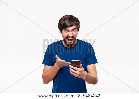 Good Looking Brunet Man In A Blue Shirt With Beard And Mostaches Shocked Looking At The Screen Of A 