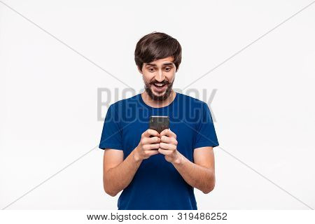 Good Looking Brunet Man In A Blue Shirt With Beard And Mostaches Surprised Looking At The Screen Of 