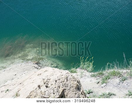 Top View Of The Clear Clear Water Of The Lake And The White Rocky Shore