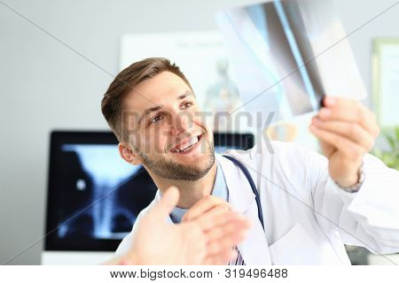Portrait Of Smiling Doctor Delighting Good X-ray Picture Results. Physician Looking At Sciagram With