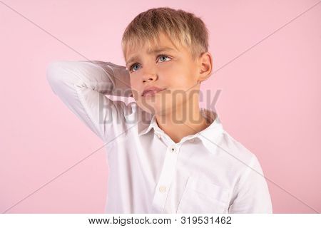 Photo Of Puzzled Boy With Stubble, Scratches Head, Looks In Bewilderment, Dressed In Casual White Sh