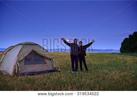 Family traveling and camping, twilight, posing near tent. Beautiful nature - field, forest, stars and moon. Father and son.