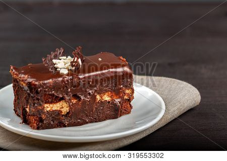 Dish With A Slice Of Chocolate Cake Stands On A Wooden Table