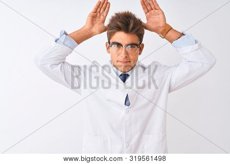 Young handsome sciencist man wearing glasses and coat over isolated white background Doing bunny ears gesture with hands palms looking cynical and skeptical. Easter rabbit concept.