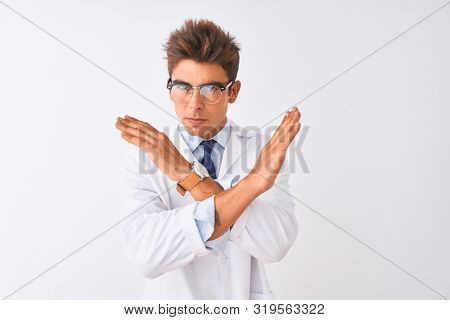 Young handsome sciencist man wearing glasses and coat over isolated white background Rejection expression crossing arms doing negative sign, angry face