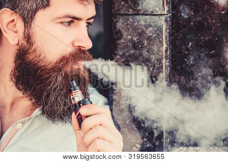 Man With Beard Breathe Out Smoke. Smoking Electronic Cigarette. Stress Relief Concept. Smoking Devic