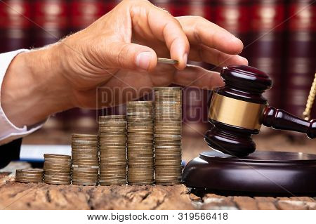 Close-up Of Human Hand Placing A Coin On Increasing Stacked Coins