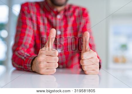Close up of hands man doing thumbs up gesture over white table