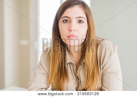 Beautiful young woman at home with serious expression on face. Simple and natural looking at the camera.