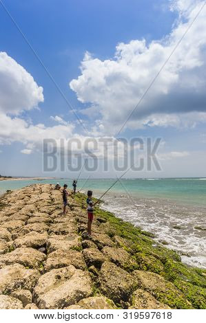 Kuta, Indonesia - October 21, 2018: Boys Fishing On The Pier Of Seminyak On Bali, Indonesia