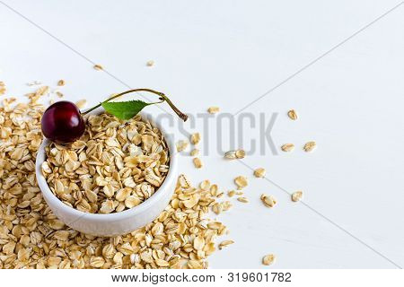 Oatmeal In A Cup Of Cherries On A White Wooden Table. There Is A Place For Your Text. The Concept Of