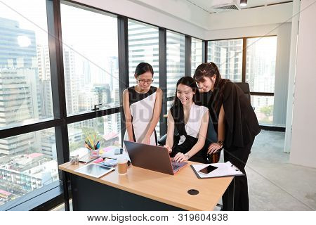3 Asian Employees Of A Company Are Updating Some Information With Smiling And Laughing Face From Com
