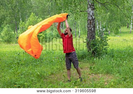 Young Man Takes Air Into An Air Lounger. Lamzak Man Tries To Inflate An Air Sofa. In The Forest Back