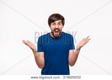 Good Looking Brunet Man In A Blue Shirt With Beard And Mostaches Shouting Shrugging His Shoulders Be