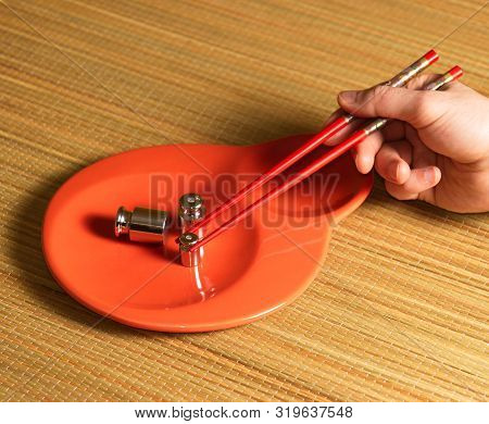 Metallic Weight And Sushi Chopstic On A Dish