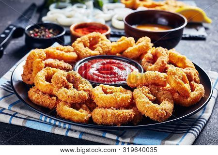 Close-up Of Crispy Calamari Rings, Deep Fried Breaded Squid Rings Served With Tomato Sauce On A Blac