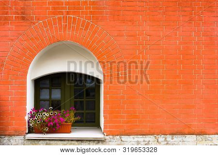 Little Old Vintage Arcked Window Of The Ground Floor Decorated With Flowers On Red Bricks Wall. Trav
