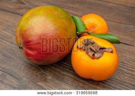 Mango, Mandarin And Persimmon / Sharon Fruit On A Wooden Table