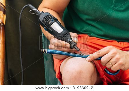 Close Up Of A Man Using A Machine To Make The Details On A Wooden Stick