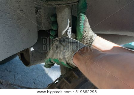 Hands In Defense Gloves Mechanics To Repair The Suspension On The Car. Work With A Wrench. Self-repa