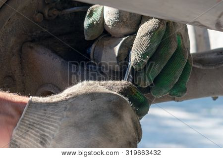 Hands In Defense Gloves Mechanics To Repair The Suspension On The Car. Work With A Wrench. Self-repa