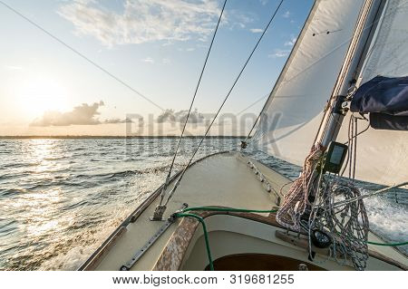 Sailing Boat Sailing Fast Into The Sunset On Choppy Sea