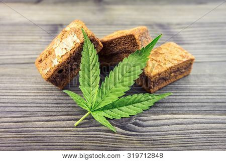Cannabis Hash Brownies With Cannabis Leaf On Wooden Table