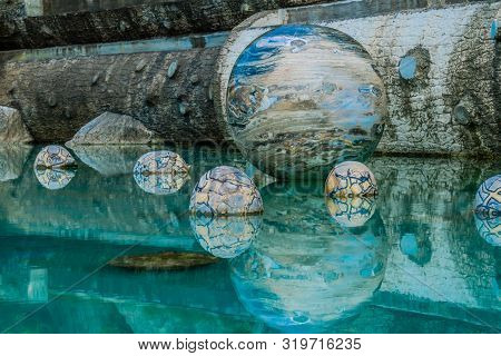 Sejong, South Korea; August 8, 2019: Marble Sphere Surrounded By Smaller Spheres In Pool Of Water At
