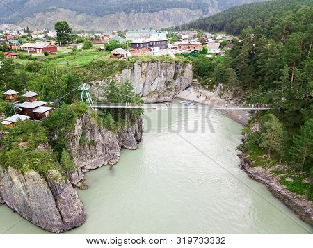 A Small Suspension Bridge With Columns On The Rocky Mountains Along Which People Go When Traveling T