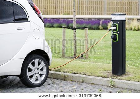 Electric Car Charging With Cable And Vehicle Charge Point At Carpark
