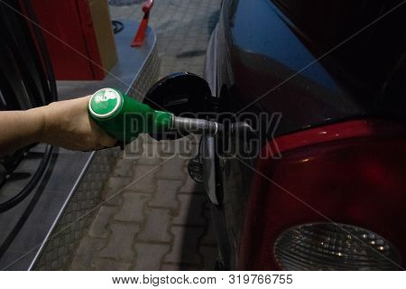 Close Up Woman Tucks Black Car At Gas Station With Her Hand
