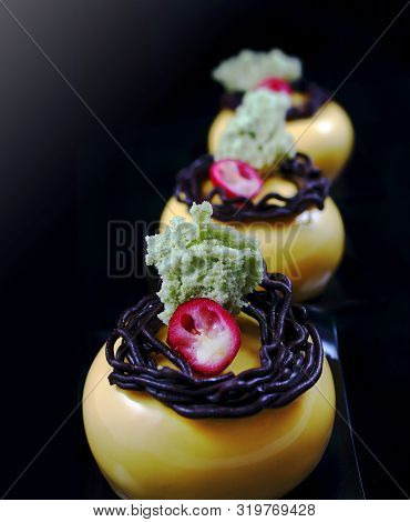 Orange Mousse Desserts With Chocolate Nest Decoration, Cranberry And Pistachio Sponge, Side Light