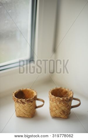 Two Wicker Mugs On The White Window Sill