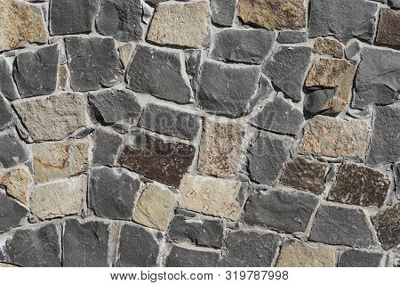 Decorative Wall Of Artificial Torn Stone In Brown Tones. Stone Masonry In Geometric Pattern As Backg