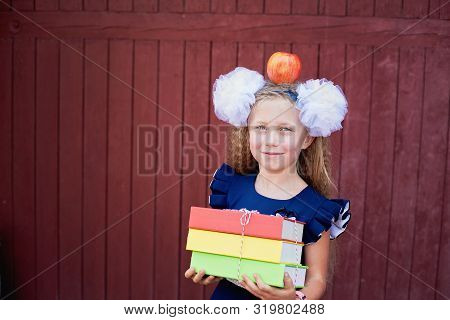 Portrait Of Happy School Girl Standing With Red Apple On Head.