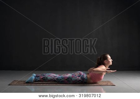 Sporty Woman Practicing Yoga, Doing Salabhasana Pose Variation