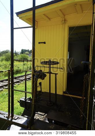 Yellow Antique Steam Train Car Close-up Shows The Ladder, Wheel, And Mechanical Details Between Cars