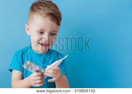 Ill Young Child With A Thermomether, Measuring The Height Of His Fever And Looking Into The Camera