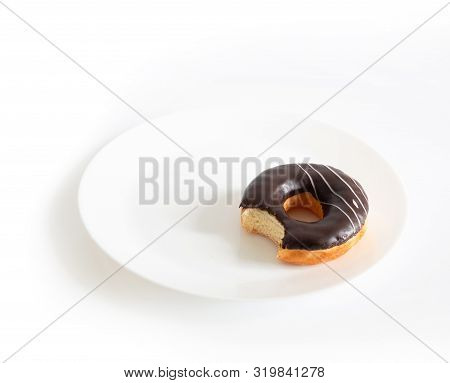 Eaten Chocolate Donut Isolated On White Background. Doughnut Has Been Bitten On A White Plate