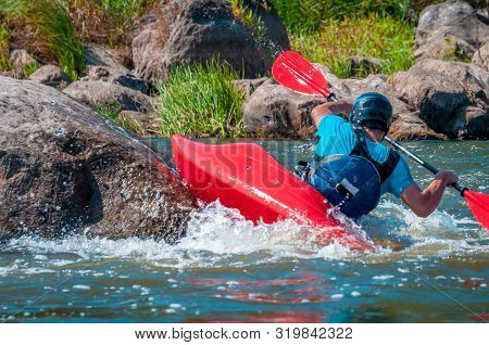 Playboating. A Man Sitting In A Kayak With Oars In His Hands Performs Exercises On The Water. Kayaki