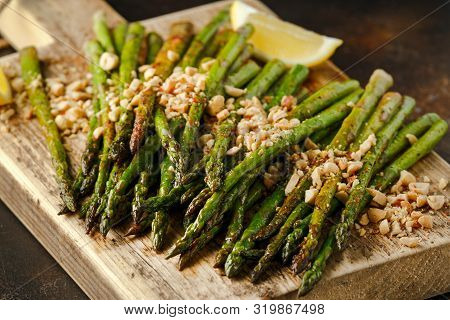 Fried Asparagus Tips Served With Crispy Crushed Peanuts On Wooden Board
