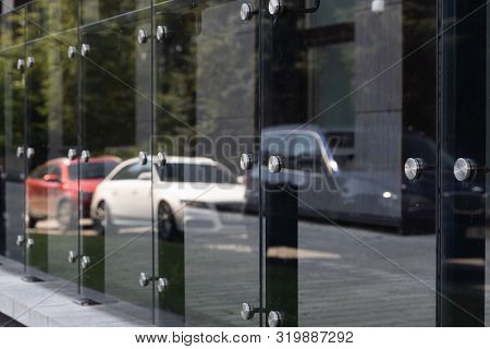 Diagonal View Of Glass Windows Or Wall With Round Steel Elements With Cars And Trees Reflection On I
