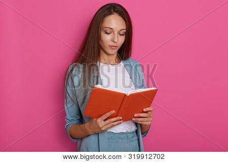 Close Up Portrait Of Young Women Reading Something In Notebook Isolated Over Rosy Background, Looks 