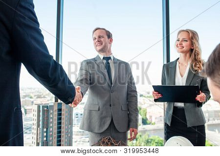 Business Meeting Of Architects And Investors Shaking Hands Finishing Deal, Model Of Modern Multi Sto