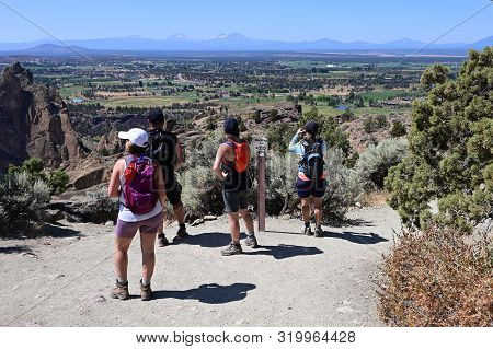 Hikers On Misery Ridge Trail In Smith Rock State Park Near Terrebonne, Oregon On A Cloudless Summer 