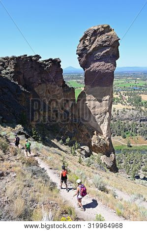 Hikers On Misery Ridge Trail In Smith Rock State Park Near Terrebonne, Oregon On A Cloudless Summer 