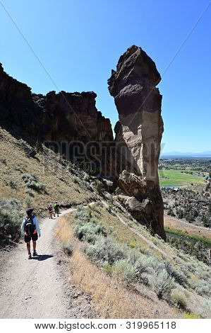 Hikers On Misery Ridge Trail In Smith Rock State Park Near Terrebonne, Oregon On A Cloudless Summer 