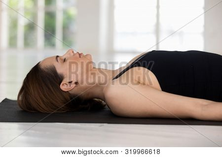 Young Woman With Closed Eyes Practicing Yoga, Savasana, Corpse Pose